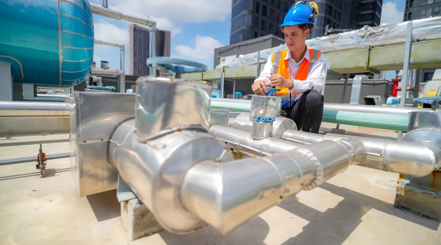 Hombre realizando revisión de algunas tuberías de paso para ventilación sostenible gracias al funcionamiento de los chillers.